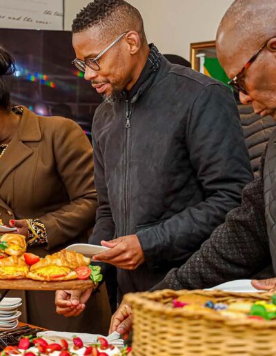 Guests serving themselves from a vibrant buffet table at a professional indoor catering event, showcasing variety and presentation in corporate catering services