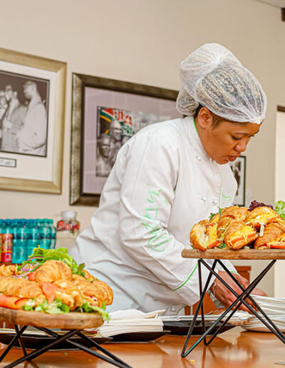 Catering professional setting up fresh sandwich platters at an indoor venue, showcasing attention to detail in event catering logistics