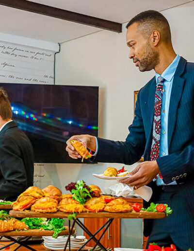 Smartly dressed guest choosing from a spread of gourmet croissants at a catered function, highlighting premium business catering services