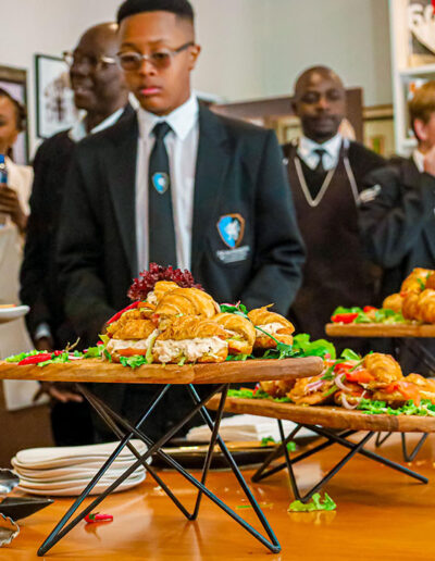 Corporate catering team serving fresh sandwiches and pastries at a business function with professional staff.