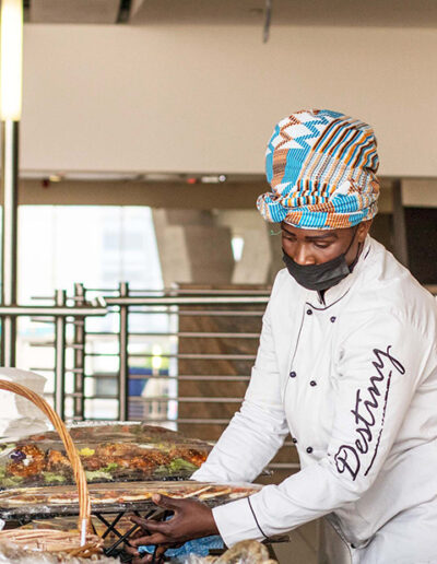 Chef in traditional headwear preparing a catered buffet station, showcasing cultural inclusivity and corporate catering expertise