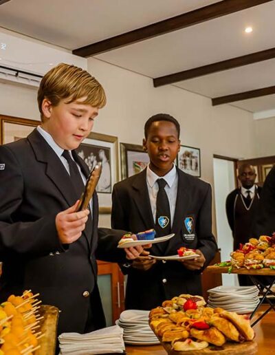 School boys in uniform selecting food from buffet table at a catered event