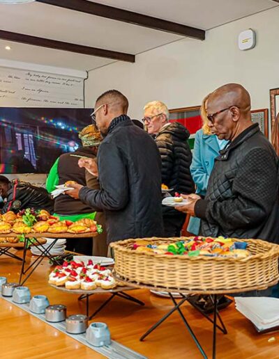 A group of guests queuing to select pastries and canapés at an elegant indoor event, demonstrating efficient buffet catering services