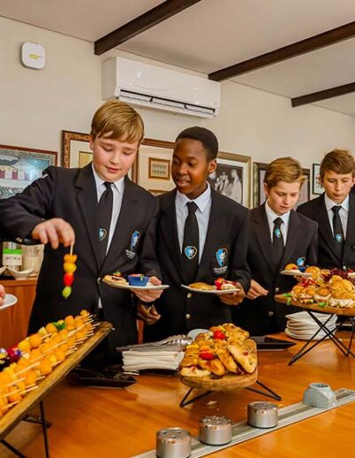 School boys in uniforms selecting finger foods from buffet table at a catered event